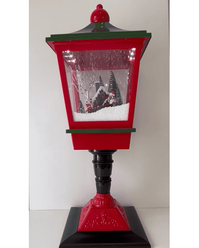 Luz de Navidad: farol rojo y verde con escena iluminada y nieve en movimiento.